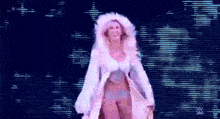 a woman in a white coat is walking on a stage