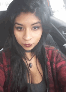 a woman in a plaid shirt is sitting in a car and taking a selfie