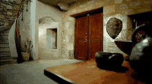 a stone wall with a wooden door and a staircase in the background
