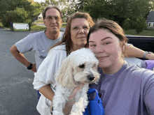 a woman in a purple shirt holds a white dog