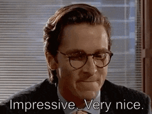 a man wearing glasses and a suit is smiling .