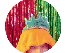 a person wearing an orange hoodie and a green happy birthday crown