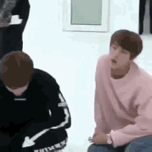 a group of young men are sitting on the floor in a room .