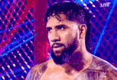 a man with a beard and a tattoo on his chest is standing in front of a cage .