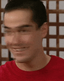 a close up of a man 's face with a red shirt on smiling .