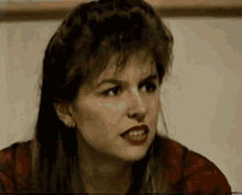 a close up of a woman 's face with a red shirt on