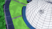 an aerial view of a dome shaped building with a blue roof surrounded by grass .