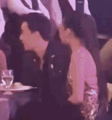a man and woman are sitting next to each other at a table with glasses of water .