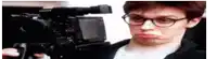 a man with glasses is holding a camera and making a funny face .