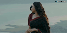 a woman in a black and red saree is standing next to a man in a red shirt