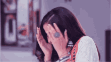 a woman covering her face with her hands while wearing a ring on her finger