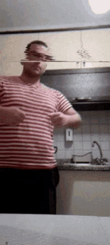 a man in a red and white striped shirt stands in front of a kitchen sink