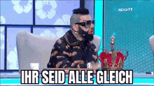 a man with a beard and sunglasses is sitting in a chair with a crown on it .