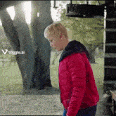 a boy in a red jacket is standing in front of a tree with a viggle.ai logo behind him