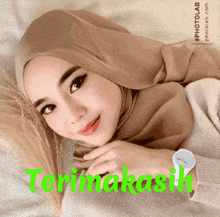 a woman wearing a hijab and a watch has the word terimakasih in green