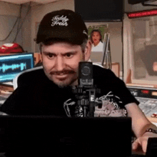 a man wearing a teddy fresh hat is sitting in front of a microphone .