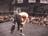 a wrestler is carrying another wrestler on his back in a wrestling ring .