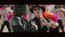 a man in a hat is dancing with another man in a suit and tie .