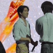a man in a white shirt is holding a microphone and talking to another man .