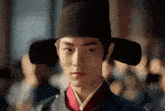 a young man wearing a black hat and a red collar