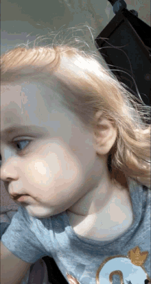 a little girl is wearing a gray shirt with a swan on it
