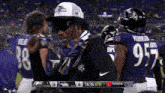a man wearing a ravens hat stands in front of a scoreboard that says toyota