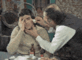 a man is getting his ear examined by another man with a bottle of medicine in front of him