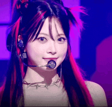 a woman with red and black hair is wearing a microphone and a necklace with spikes