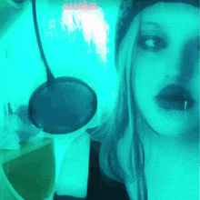 a woman wearing a hat and headphones looks at the camera with a microphone in the background