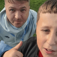 a man wearing a nike sweatshirt is giving a thumbs up to a young boy