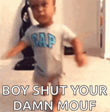 a baby wearing a gap shirt is walking and says boy shut your damn mouf