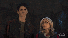 a man and a woman are standing next to each other with a disney logo behind them