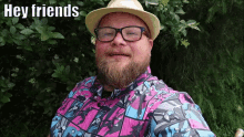 a man with a beard wearing glasses and a hat says " hey friends "