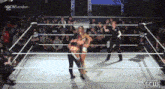 two women are wrestling in a wrestling ring with a referee .