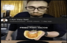 a man is holding a fried fish taco in his hand