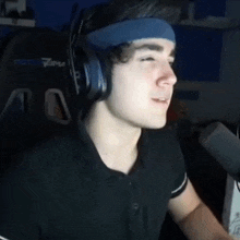 a young man wearing headphones and a headband is sitting in front of a chair that says proton tema