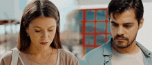 a man and a woman are standing next to each other and looking at something .