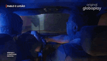 a group of men are laughing in a car with pablo e luisao in the background