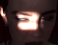 a close up of a woman 's face with the sun shining through her eye