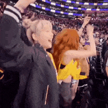 a group of people are standing in a stadium with their hands in the air