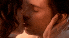 a man and a woman are kissing and the woman is touching the man 's face