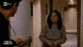 a woman wearing a shirt that says forever stands in a hallway