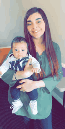 a woman is holding a baby wearing a nike shirt