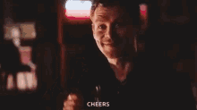a man is holding a glass of beer and smiling .