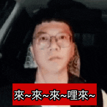 a man wearing glasses is behind a red sign with chinese writing on it