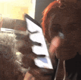 a woman with red hair is holding a cell phone in her hands