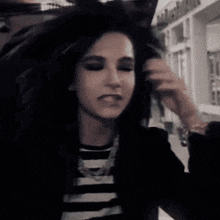 a woman in a black and white striped shirt is being touched by a man in a black jacket .