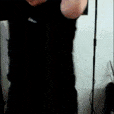 a man in a black shirt is standing in front of a mirror .