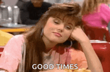 a woman is sitting at a table in a restaurant with her head on her hand and the words `` good times '' written on her face .