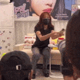 a woman wearing a mask is sitting on a couch holding a cell phone .